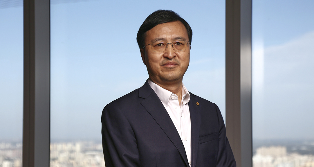 Liu Qu stands in front of windows in his office building