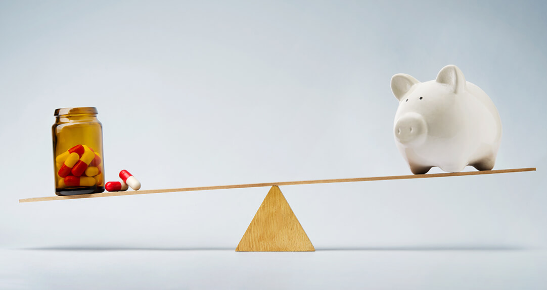 A conceptual image relevant to value-based reimbursement in pharmacy financing shows a seesaw with a piggy bank on one side and a medicine bottle with pills on the other.