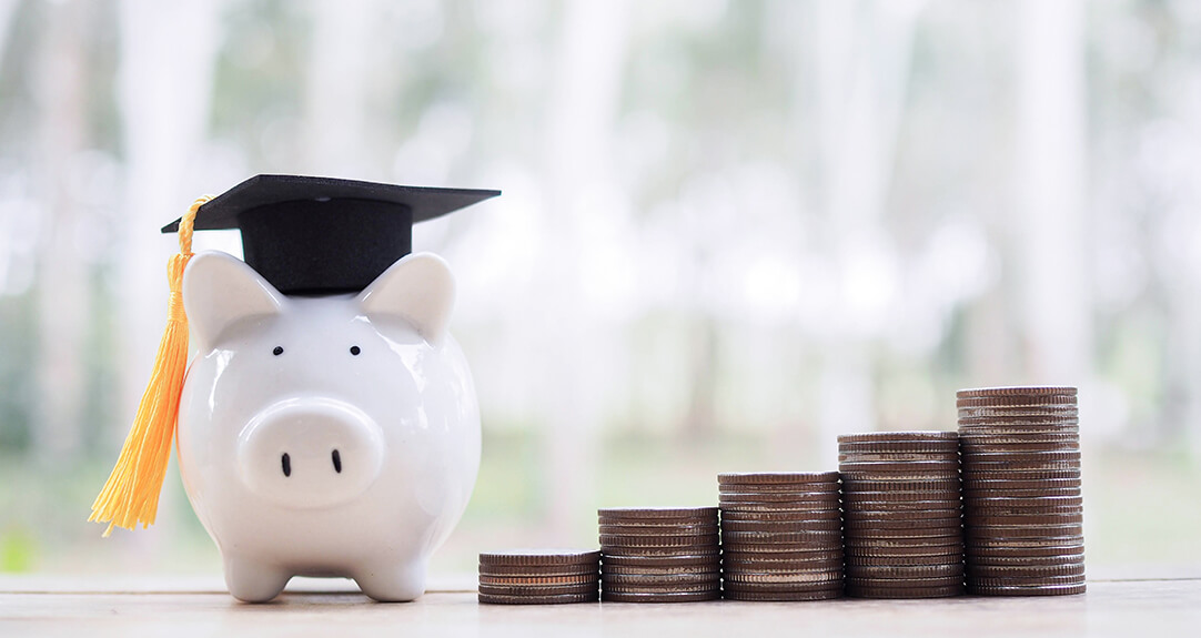 A piggy bank with a mortarboard stands next to stacks of quarters.
