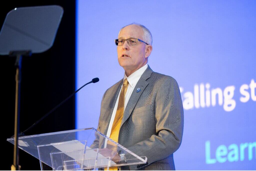 Greg Heidrich speaks at a podium during the 2026 ReFocus Conference in Las Vegas.