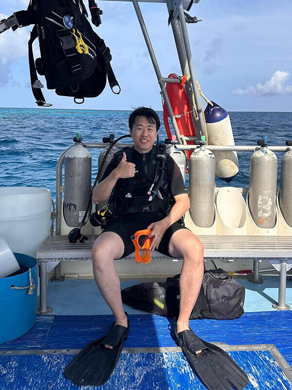 Ray sits on a boat with his scuba gear on.